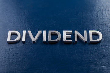 the word dividend lait by silver metal letters on classic blue color painted background with...