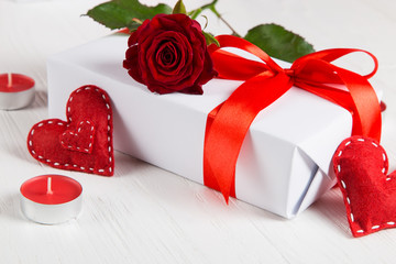 Gift with red ribbon, red rose and heart on a white background. The concept for Valentine's Day, a romantic gift to a loved one for the holiday.