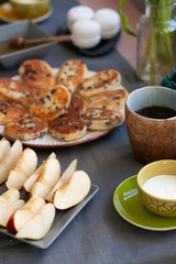 Breakfast for two: cheeses with raisins of homemade cheese, sour cream, black coffee, apple and marshmallows. On the table is a bouquet of pink tulips.