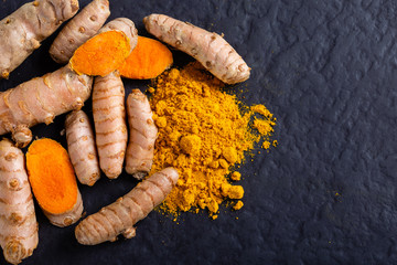 Food and drink, diet nutrition, health care concept. Raw organic orange turmeric root and powder, curcuma longa on a grunge cooking table. Indian oriental low cholesterol spices - obrazy, fototapety, plakaty