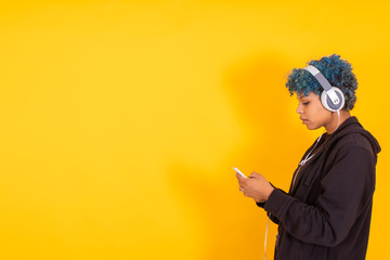 young girl or woman with mobile phone and headphones on yellow background with space - obrazy, fototapety, plakaty