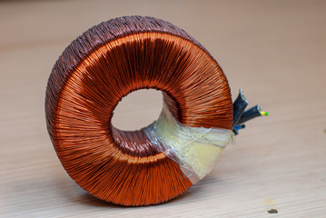 Close-up of a toroidal transformer, made up of wrapped copper coil © marco_cesarano