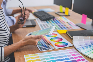 Two colleagues creative graphic designer working on color selection and drawing on graphics tablet at workplace, Color swatch samples chart for selection coloring