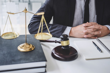 Obraz na płótnie Canvas Male lawyer or judge working with contract papers, Law books and wooden gavel on table in courtroom, Justice lawyers at law firm, Law and Legal services concept