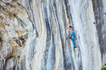 Fototapeta premium Caucasian young man climbing challenging route on cliff