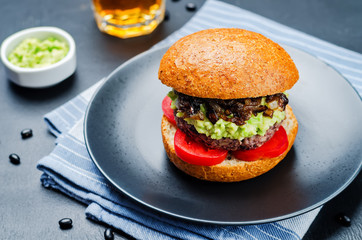 black bean burger with mashed avocado, caramelized onions and tomatoes