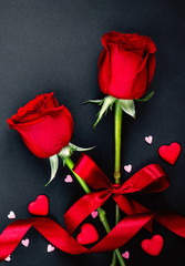 Beautiful valentines day background with red roses and hearts on black background. Flat lay, Copy space