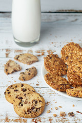White plate with healthy snack granola whole grain cookies and glass cup of milk on wooden surface. Healthy food and lifestyle concept