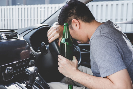 Young Asian Man Drives A Car With Drunk A Bottle Of Beer And Fall Asleep Behind The Wheel Of A Car