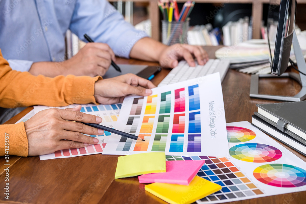 Poster Two colleagues creative graphic designer working on color selection and drawing on graphics tablet at workplace