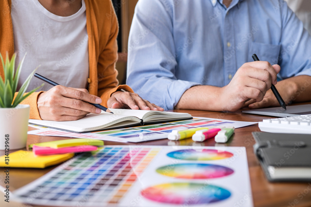 Poster Two colleagues creative graphic designer working on color selection and drawing on graphics tablet at workplace
