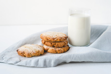 Stacked cookies on a linen napkin and a glass of milk. Close up.