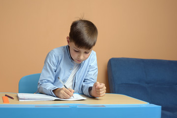 Cheerful Caucasian schoolboy in uniform doing task at classroom. First time to school. Back to school.