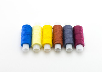 Multi-colored bobbins with threads on a bol background.
