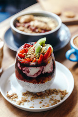 Healthy breakfast with chia strawberry pudding, oatmeal bowl with banana, peanut butter, blackberries, raspberries, nuts, seeds and goji berries