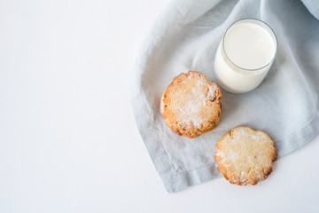 Stacked cookies on a linen napkin and a glass of milk. Close up. Top view.