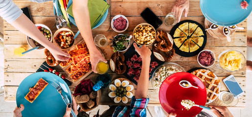 Above view of wooden trendy table full of friends people and home made food to celebrate and stay together having fun in friendship - concept of caucasian men and women mixed ages