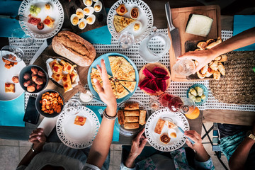 Vertical view of table with blue dishes and lot of coloured food - people in firendship enjoy eating together in party celebration at home for holiday
