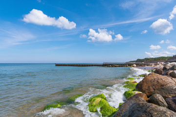 The big stones and wooden breakwaters protect the coast of the Baltic Sea. Landscape on a sunny summer day. City Pionersky, Kaliningrad region
