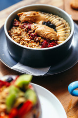 Healthy vegan breakfast with oatmeal bowl with banana, peanut butter, blackberries, raspberries, nuts, seeds and goji berries.