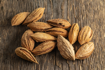 Selected inshell almonds on a background of rough wood texture. Selective focus.