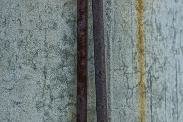 two brown rusty iron gas pipes on a gray concrete wall of a building