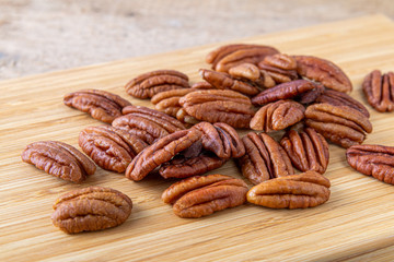 Pecans nuts on wooden cutting board