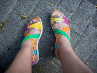 brightly coloured sandals on a grey pavement 