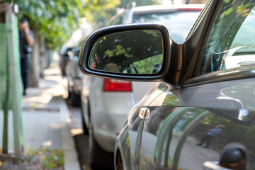 Naklejka premium Close up of rearview mirror of a car parked near curb on the side of the street on a parking lot.