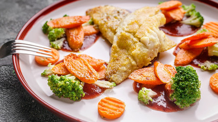 Close up fillet of sea bass with vegetables. Baked fish, cauliflower and carrots