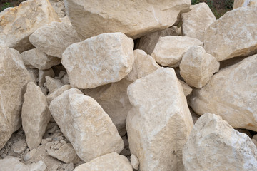 Big pile of large sand stones laying on the ground of construction site.