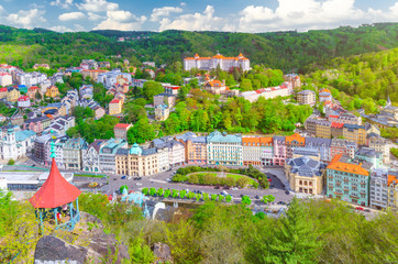 Karlovy Vary (Carlsbad) historical city centre top aerial view with colorful beautiful buildings, Slavkov Forest hills with green trees and Deer Jump Jeleni Skok Lookout, West Bohemia, Czech Republic © Aliaksandr