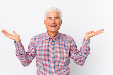 Senior caucasian man isolated makes scale with arms, feels happy and confident.