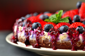 Tart with fresh strawberries, blueberries and cherry jam. Low depth of field
