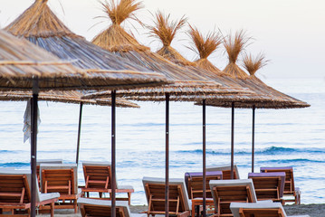 Sun umbrellas and beach beds on the sea coast.Sun beds with a thatched roof on the seashore.