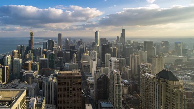 Time lapse day to night of Arial view of Chicago downtown skyscrapers over Lake Michigan with cloudy sky.