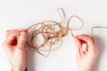 Man untangles a tangled thread. Top view isolated on a white background.