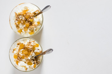 Crumbly cottage cheese with honey, banana, golden raisins and nuts on a light background