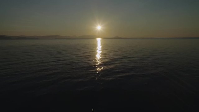 Flying above water towards the sun. Aerial, drone video. Video 1 of 5.