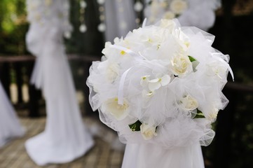 white wedding arch decorated with white flowers roses and pearls. Wedding decor
