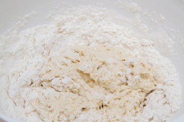 Fototapeta na wymiar Cooking dough in a white plastic bowl at home