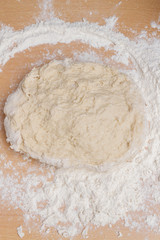 Kneading dough with flour on a wooden table at home