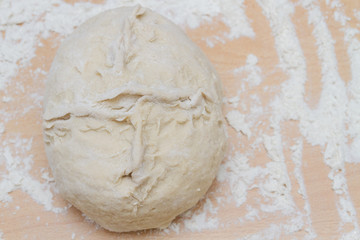 Prepared kneaded dough on a wooden table at home