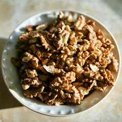 A dish full of peeled kernels of walnut closeup top view.