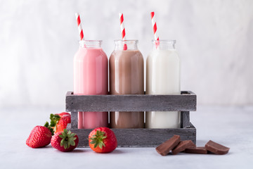 Three glass jars of neapolitan flavoured milk.