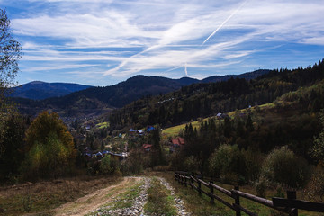 Obraz na płótnie Canvas Autumn landscape: Carpathian mountains and village below, beautiful sky with cirrus clouds.