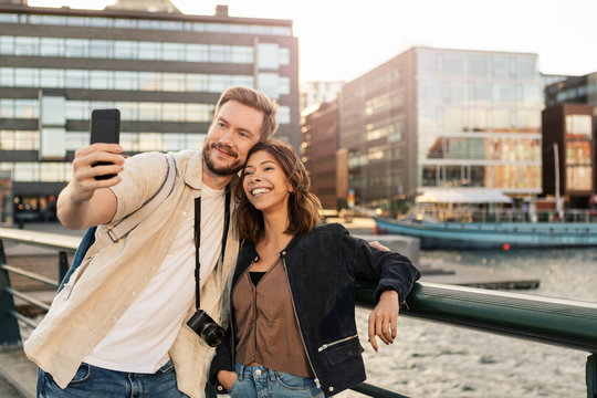Man taking selfie with girlfriend on smart phone while exploring city