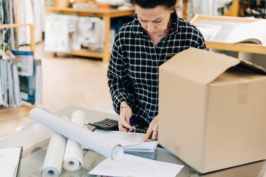 Saleswoman reading document with box on table in store