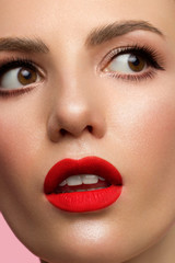 Naklejka premium Half face Girl with perfect clean skin. The woman looks at the camera in surprise, opening her mouth. Youth and skin care concept. Extra long eyelashes, eyeliner and sexy puffy lips with red lipstick