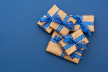 Christmas or birthday presents. Craft paper wrapped gift boxes on blue background, flat lay.